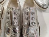 several pairs of silver shoes sitting on top of a white table