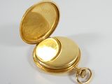 a gold pocket watch sitting on a white surface