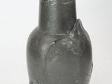 un vase noir posé sur une surface blanche