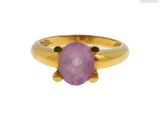 gros plan d'une bague en or avec une pierre rose