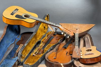 a guitar, a violin case, and other musical instruments on a table