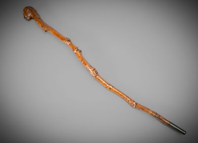 a close up of a wooden walking stick on a gray surface