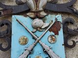a blue plaque with two guns on it on the side of a building