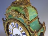 a green and gold clock with a bird on it