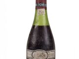 une vieille bouteille de vin posée sur une surface blanche
