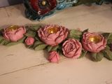 pink roses and candles on a table with a blue vase in the background