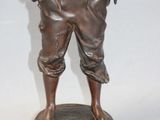 bronze statue of a man with a hat on a wooden base