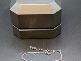 a silver box with a silver chain on a table