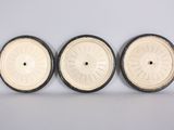 three white and black wheels sitting on top of a white surface