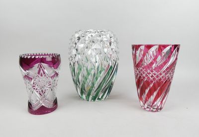 trois vases en verre de couleurs différentes posés l'un à côté de l'autre sur une surface blanche