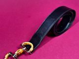 a black leather belt with a gold buckle on a pink background