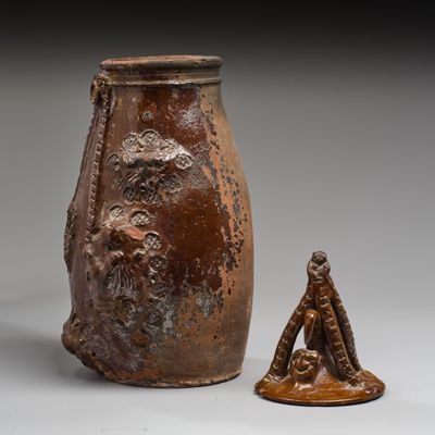 un vase marron et une petite figurine posés l'un à côté de l'autre
