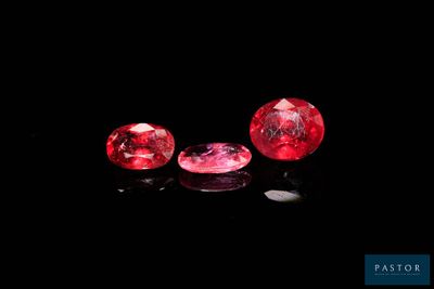 three ruby colored diamonds on a black surface