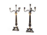 une paire de chandeliers noirs et dorés avec des bougies sur leurs socles