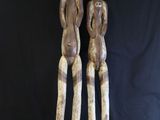 deux statues en bois représentant deux personnes debout l'une à côté de l'autre