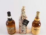 three bottles of alcohol sitting next to each other on a table