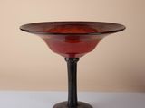 a red glass bowl sitting on top of a white table