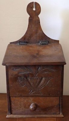 une vieille boîte en bois posée sur un parquet, près d'un mur