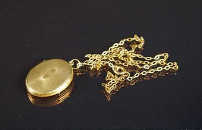 un cadenas doré entouré d'une chaîne, posé sur une surface noire
