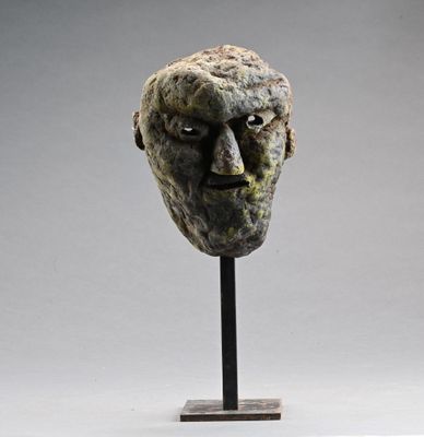 une sculpture représentant le visage d'un homme, posée sur un socle métallique