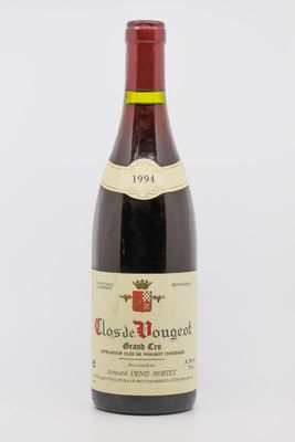 une vieille bouteille de vin rouge posée sur une table blanche