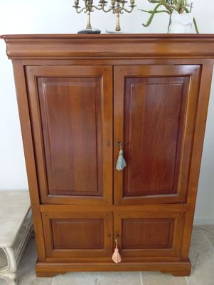 une armoire en bois à deux portes, sur laquelle est posé un vase avec des fleurs