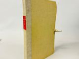 un vieux livre portant une étiquette rouge, posé sur une surface blanche