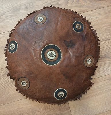 un gros objet en cuir marron posé par terre