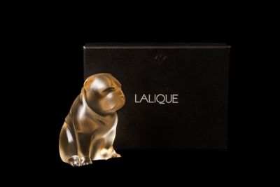 une figurine en or représentant un chien, assise devant une boîte noire