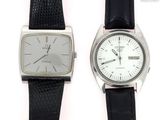 two watches sitting next to each other on a white surface