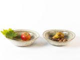 two bowls with food in them on a white surface