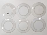 six white plates with a black dot are arranged on a white surface
