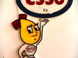 un panneau sur lequel est inscrit « Esso », avec un personnage de dessin animé tenant une pancarte