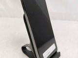 a black cell phone on a stand on a white surface