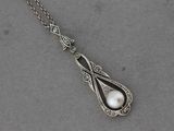 un gros plan d'un collier en argent orné d'une perle