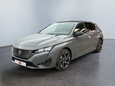 Une voiture grise est garée dans une grande pièce au sol noir.