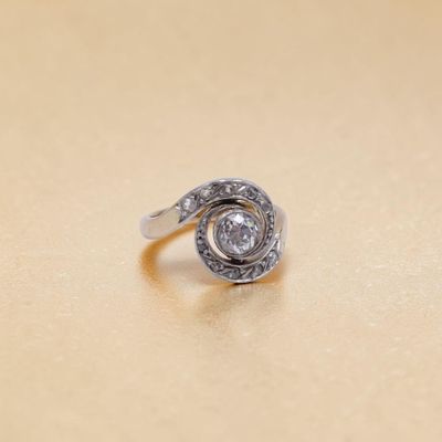 une bague en argent sertie d'un diamant, posée sur une table