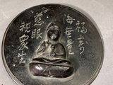 a silver coin with a picture of a buddha on it