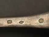 a silver spoon with holes in it on a black surface