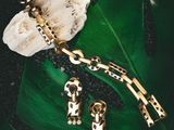 a green leaf with a gold bracelet and two charms
