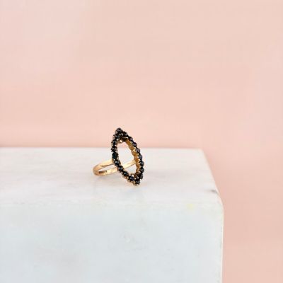 une bague en or sertie de diamants noirs repose sur un bloc de marbre