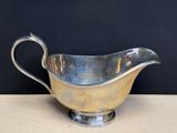 a silver gravy sitting on a table with a black background