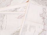 many maps of the world on a table with a cup of coffee