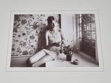 a black and white photo of a woman sitting on a window sill