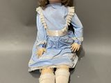 an old doll sitting on a grey surface with a gray background