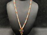 a necklace with orange and white beads on a mannequin