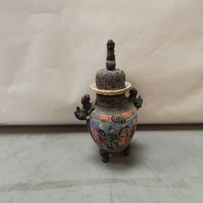 un vase muni d'un couvercle, posé par terre
