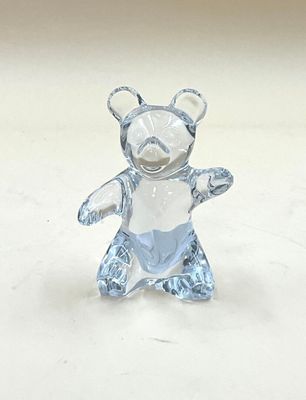 une figurine d'ours en verre posée sur une surface blanche