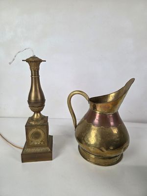 a gold pitcher and a brass candle holder on a white table