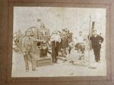 a black and white photo of a group of men standing in front of a fire engine